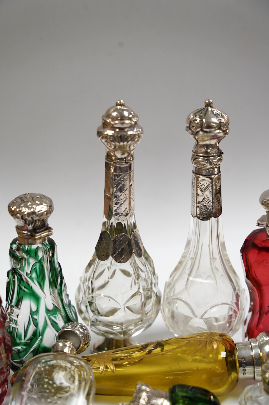 A collection of ten assorted Victorian and later silver or white metal mounted glass scent bottles, including teardrop shaped by Saunders & Shepherd, Birmingham, 1884, 12.7cm. Condition - poor to fair to good